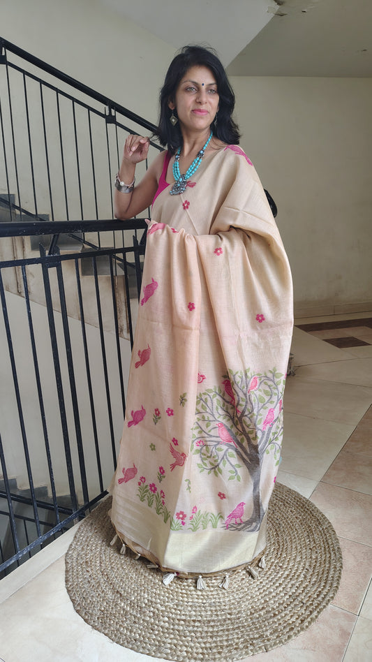 Woman wearing a beige saree with floral patterns in an indoor setting.